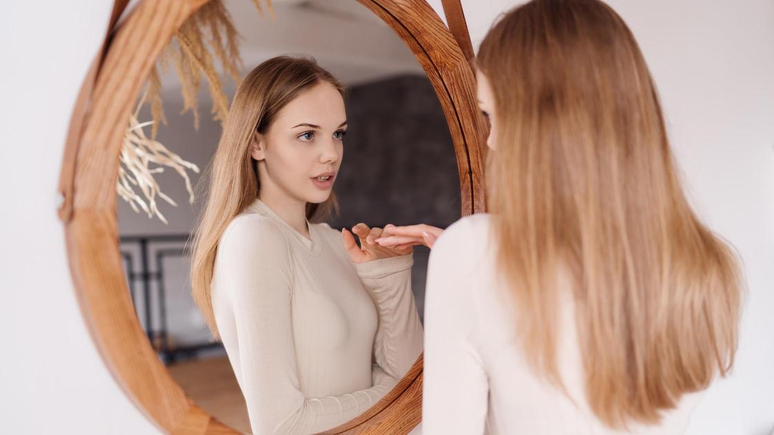 Девушка смотрит на себя в зеркало