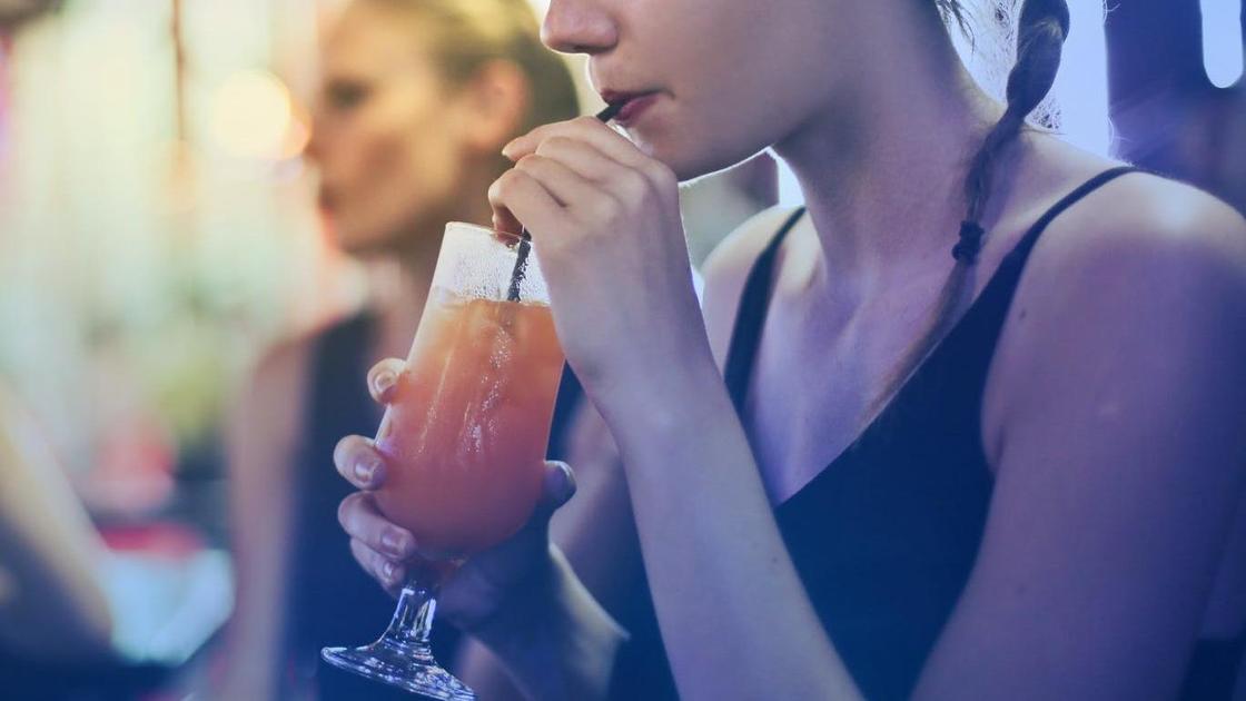 Девушка пьет коктейль в баре