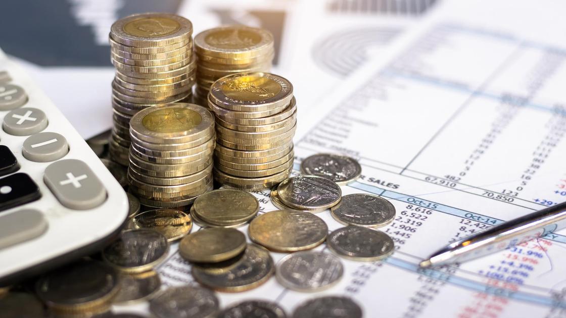Монеты, калькулятор и ручка лежат на финансовом отчете