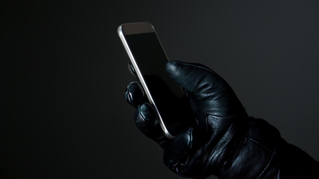 Рука в перчатке держит мобильный телефон