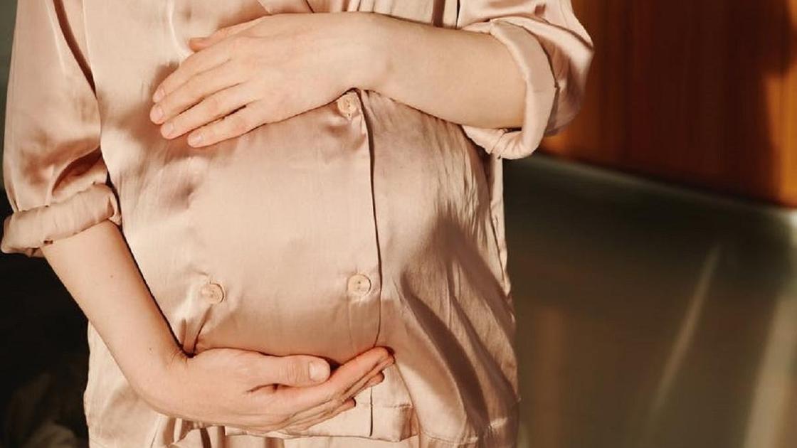 Беременная женщина держит свой живот