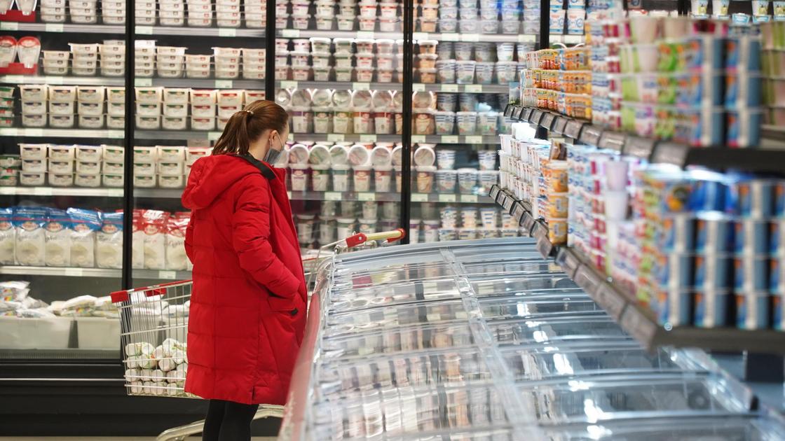 Женщина смотрит на продукты в супермаркете