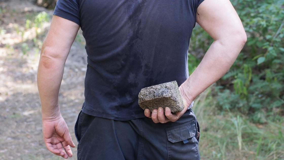Мужчина держит камень