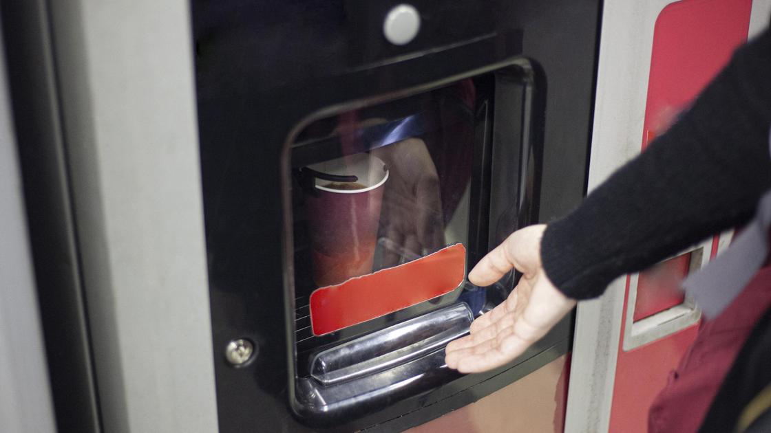 Мужчина достает кофе из автомата