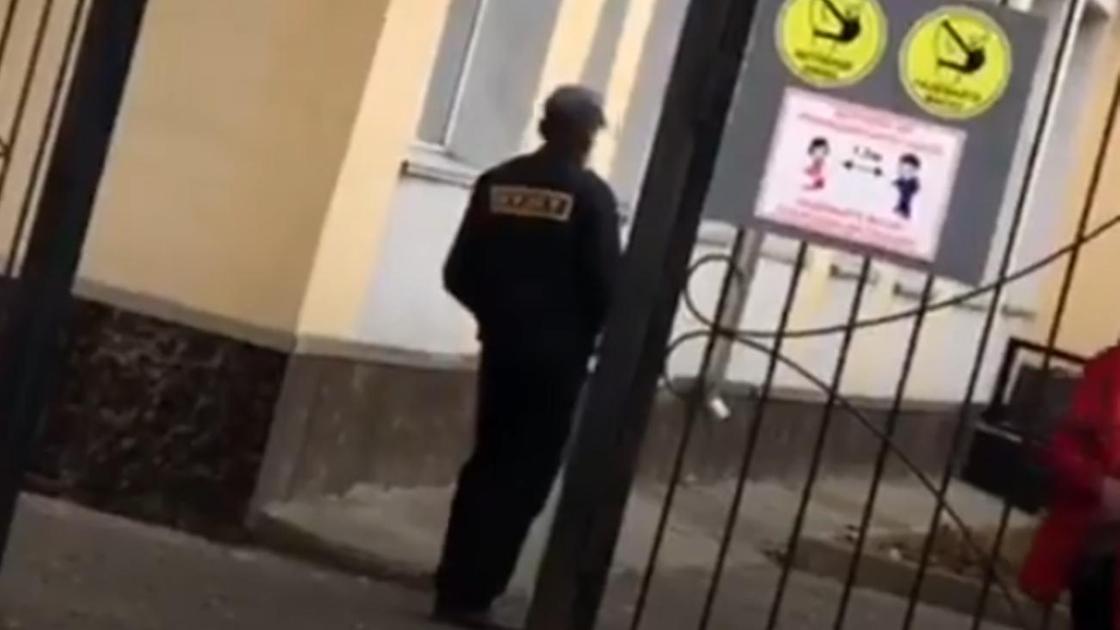 Пьяный охранник стоит возле школы