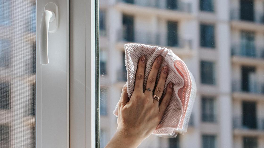 Женщина моет окно