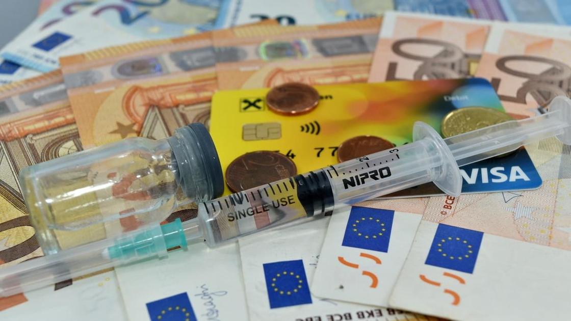 Шприц и ампула лежат на купюрах евро
