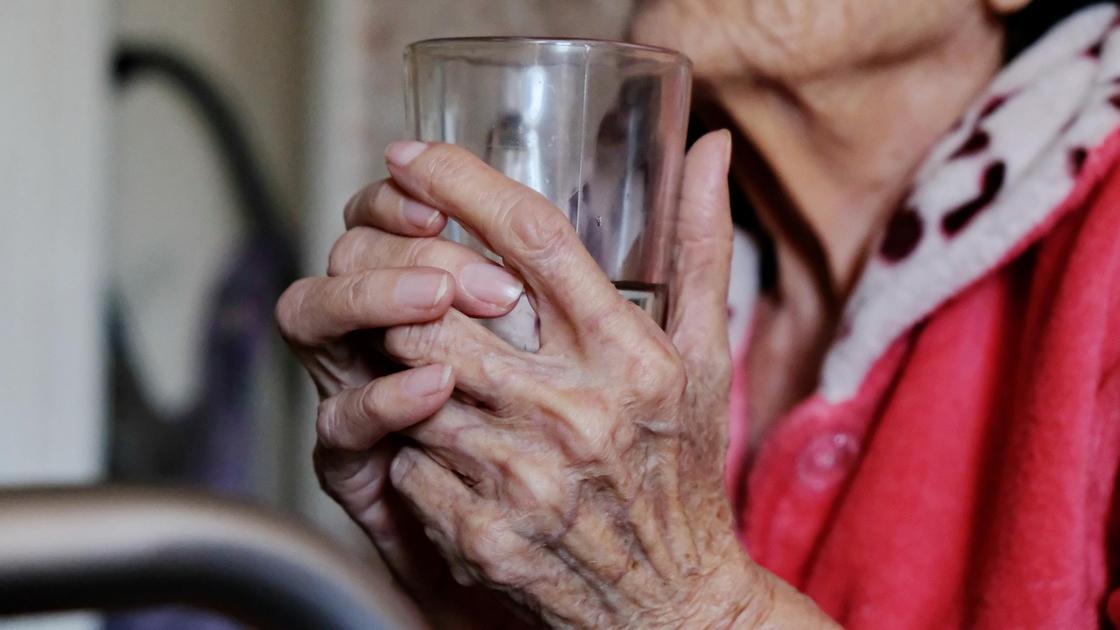 Женщина держит в руках стакан воды