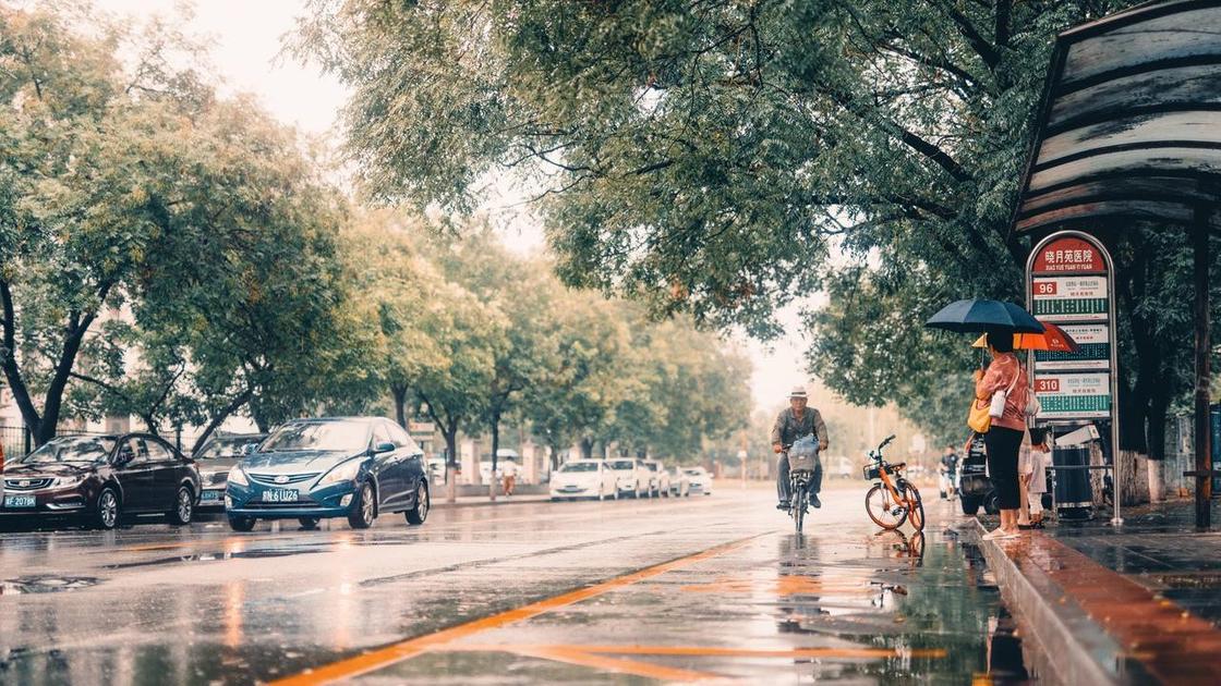 Мужчина едет на велосипеде по мокрой дороге после дождя