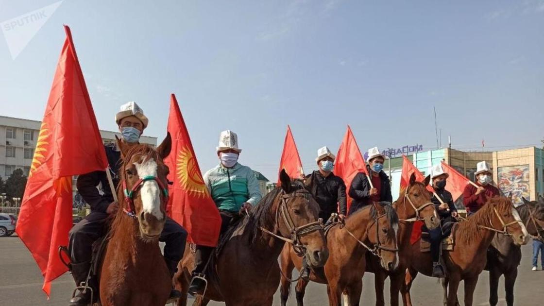 Всадники на лошадях держат флаг Кыргызстана