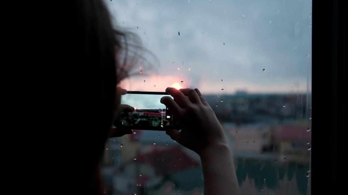 Девушка фотографирует вид из окна