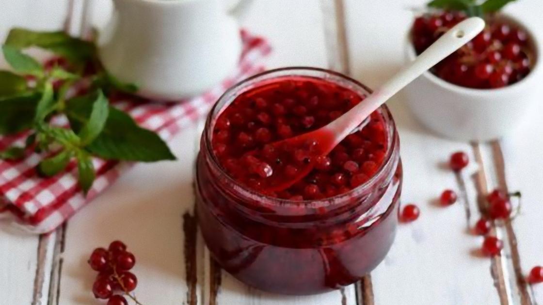 Банка с вареньем из красной смородины, красная смородина в чашке и на столе Банка с вареньем из красной смородины, красная смородина в чашке и на столе