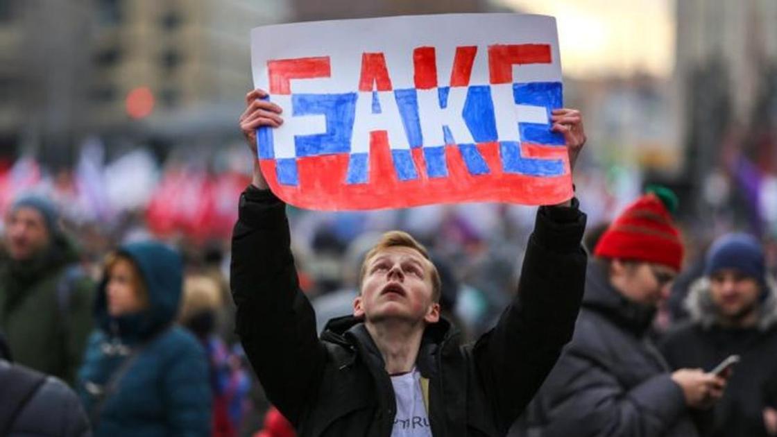парень держит плакат с надписью Fake парень держит плакат с надписью Fake