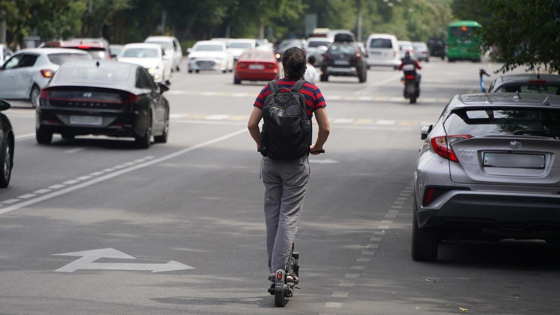 Самокат айдап кетіп бара жатқан адам
