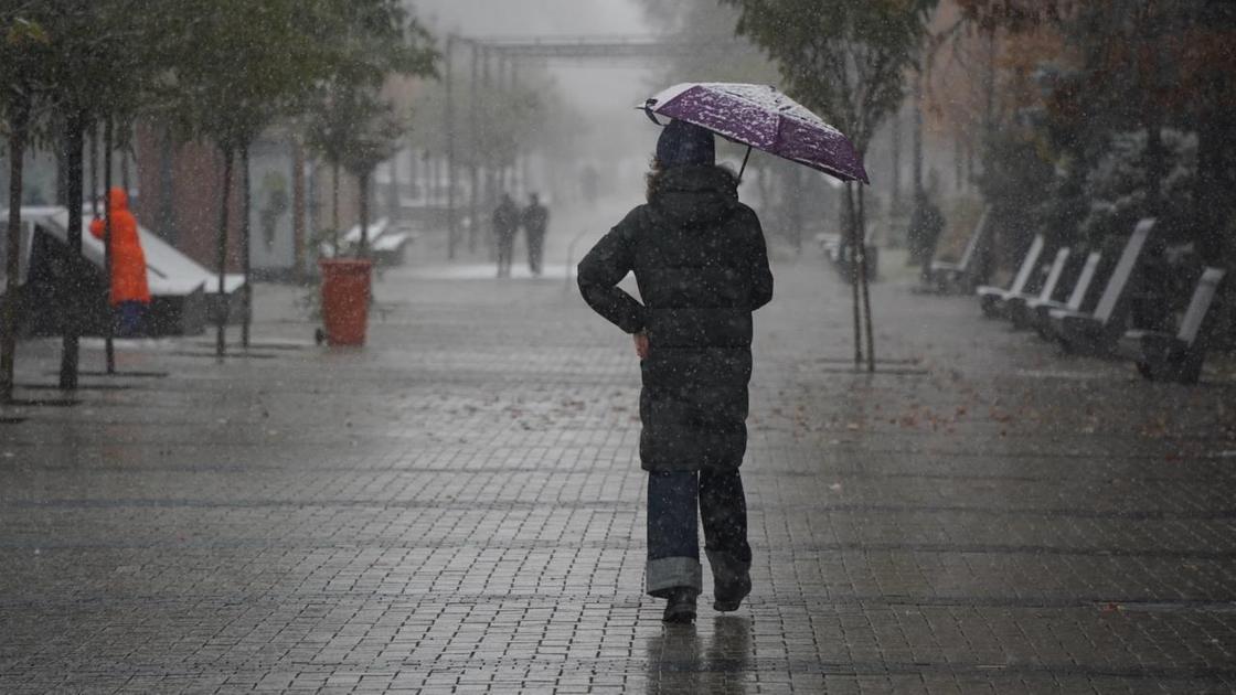 Девушка прячется от дождя под  зонтом