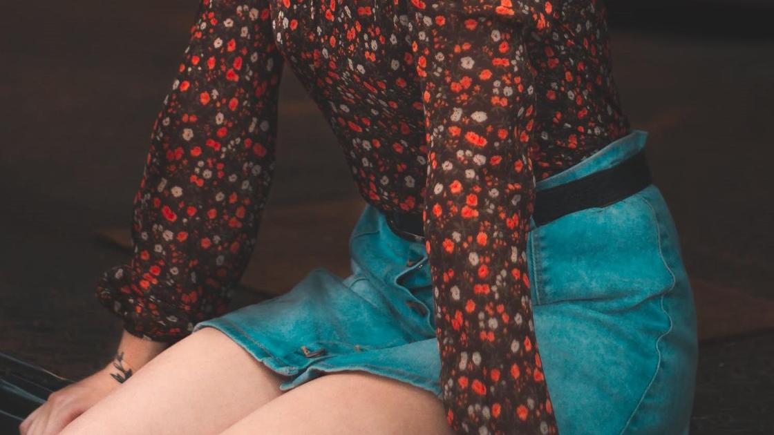 Девочка в юбке и блузке сидит на коленях