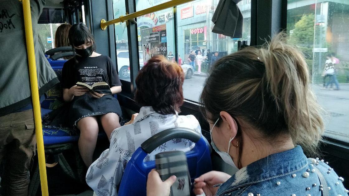 Жители Алматы в масках сидят в автобусе