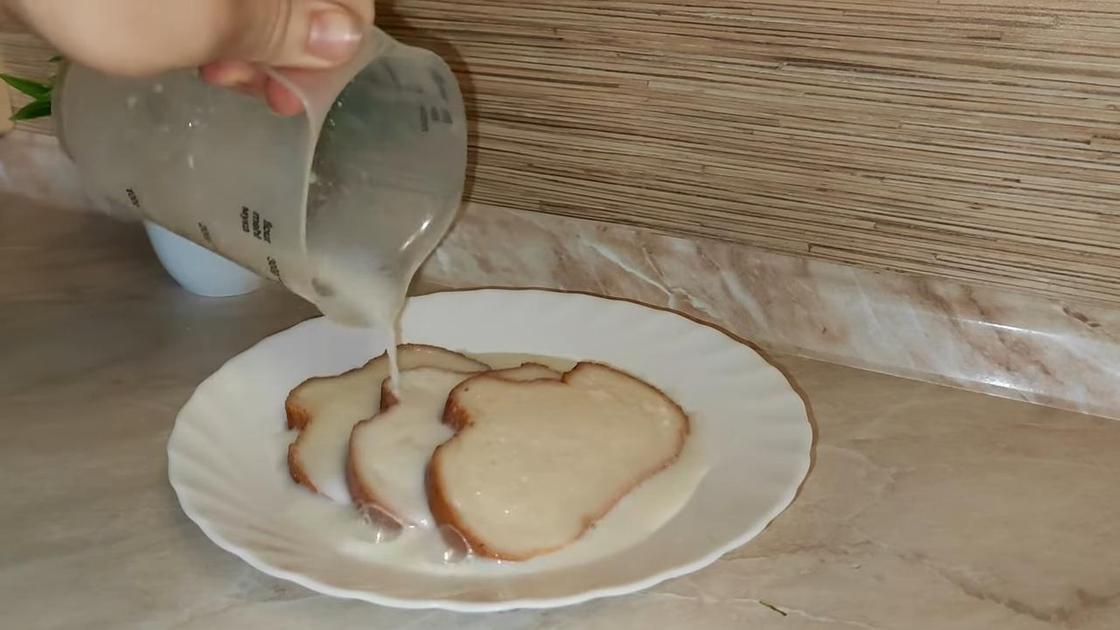 Кусочки белого хлеба на тарелке поливают молоком из мерной чаши