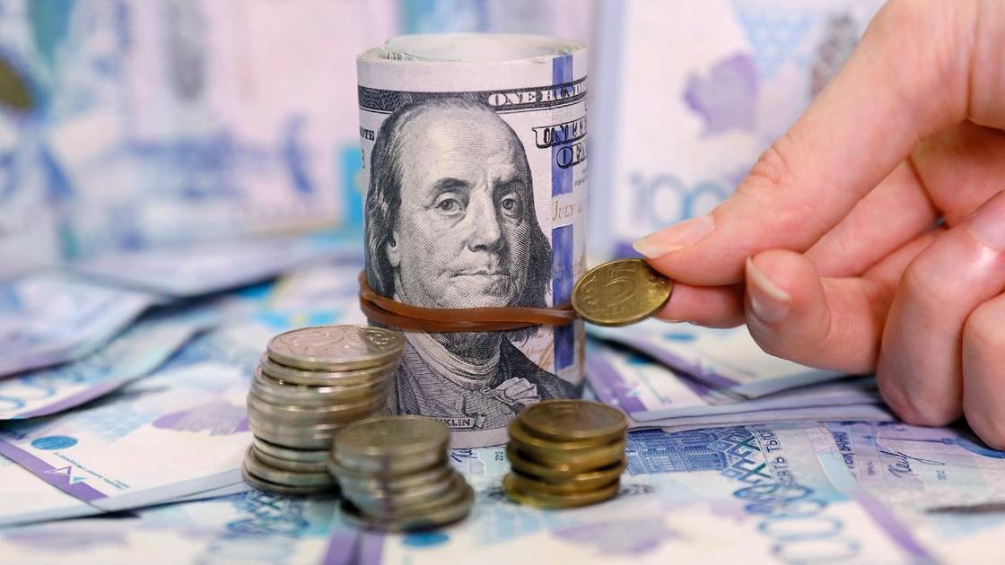 Женщина сравнивает монеты тенге с пачкой долларов