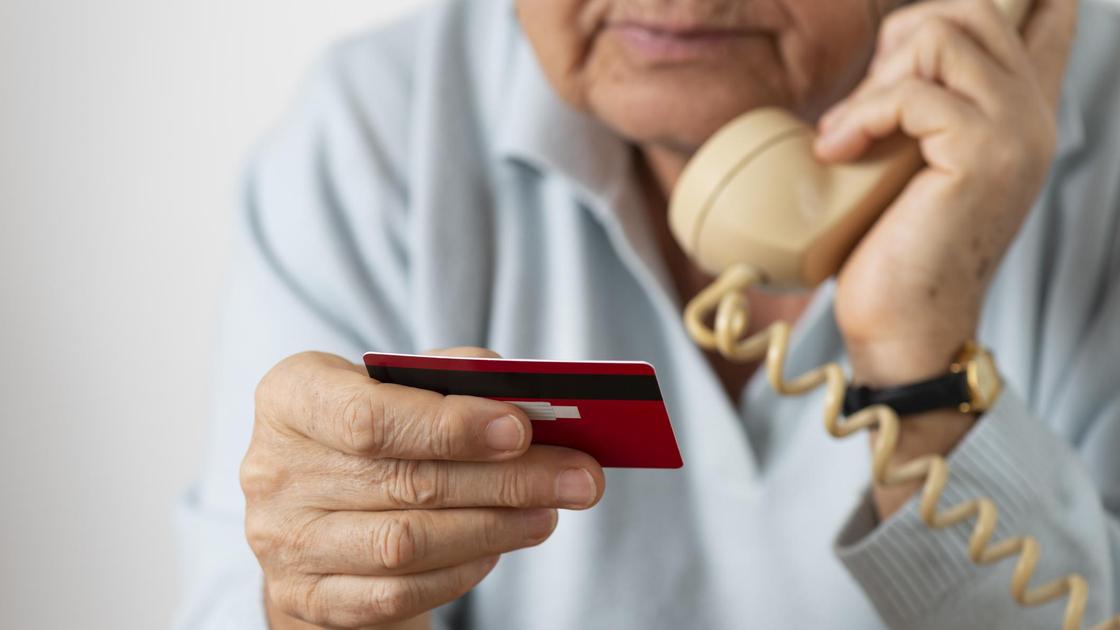 Пенсионерка держит телефон и банковскую карту