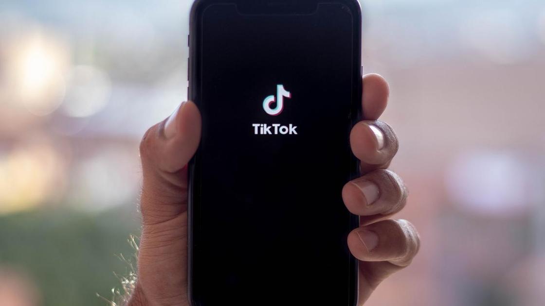Человек держит телефон с логотипом TikTok