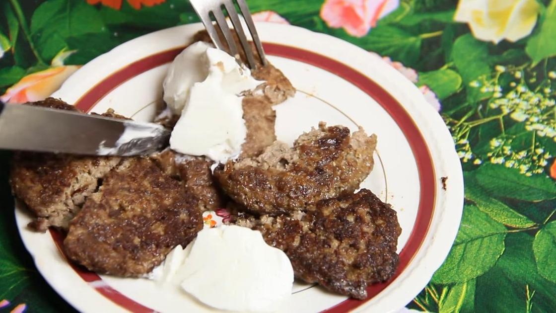 Печеночные котлеты со сметаной на тарелке