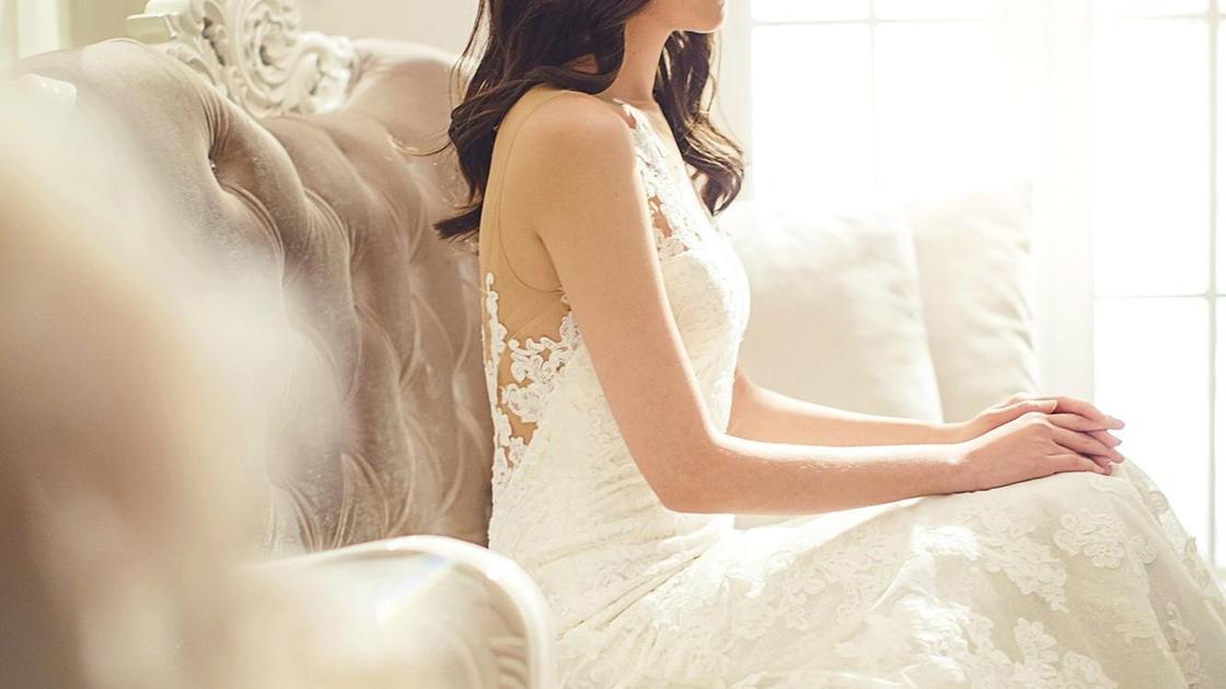 Девушка в свадебном платье сидит на диване