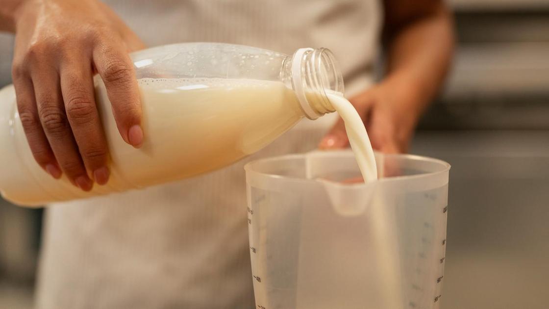 Молоко переливают из бутылки в мерный стакан