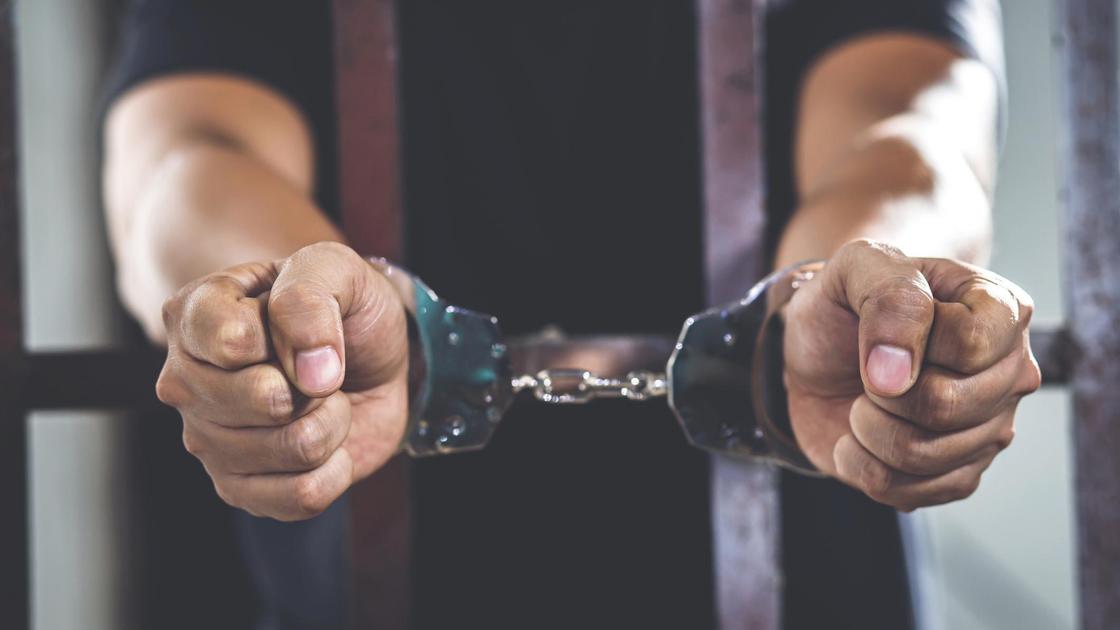 Мужчина в наручниках за решеткой
