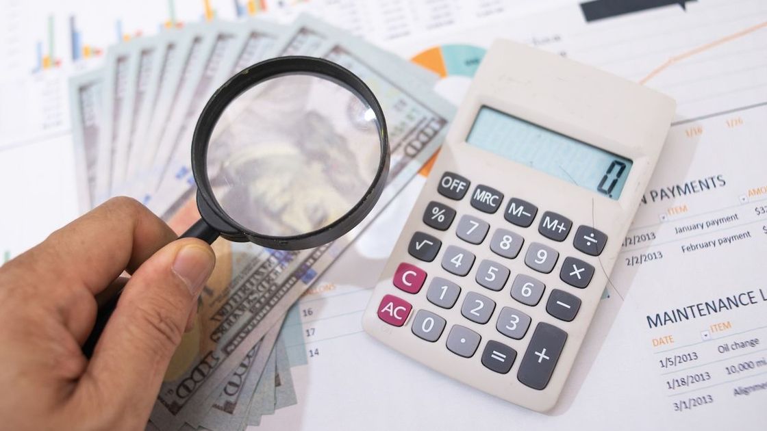 Мужчина рассматривает купюру через увеличительное стекло