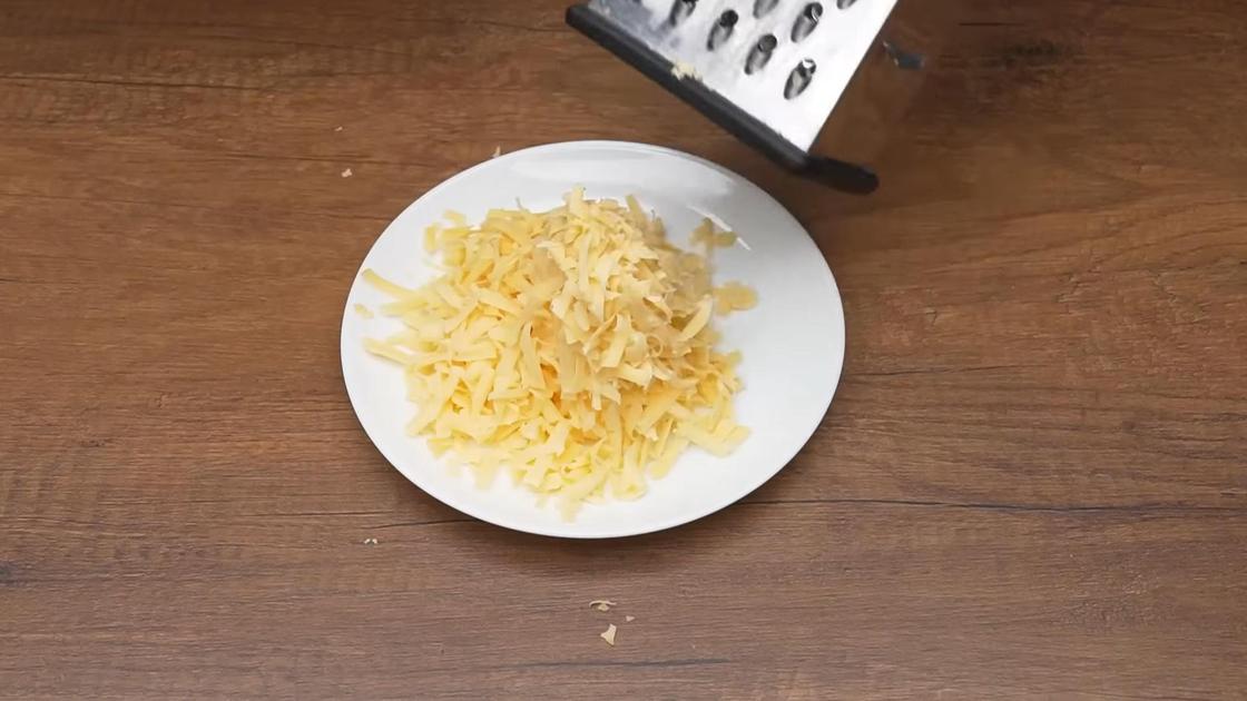 Натертый твердый сыр в тарелке