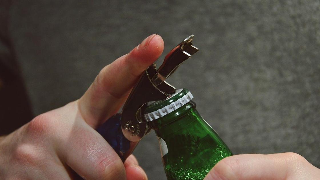 Мужчина открывает бутылку пива