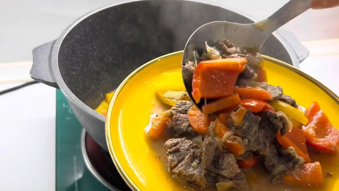 Тушеное мясо и овощи ложкой выкладывают на сервировочную тарелку