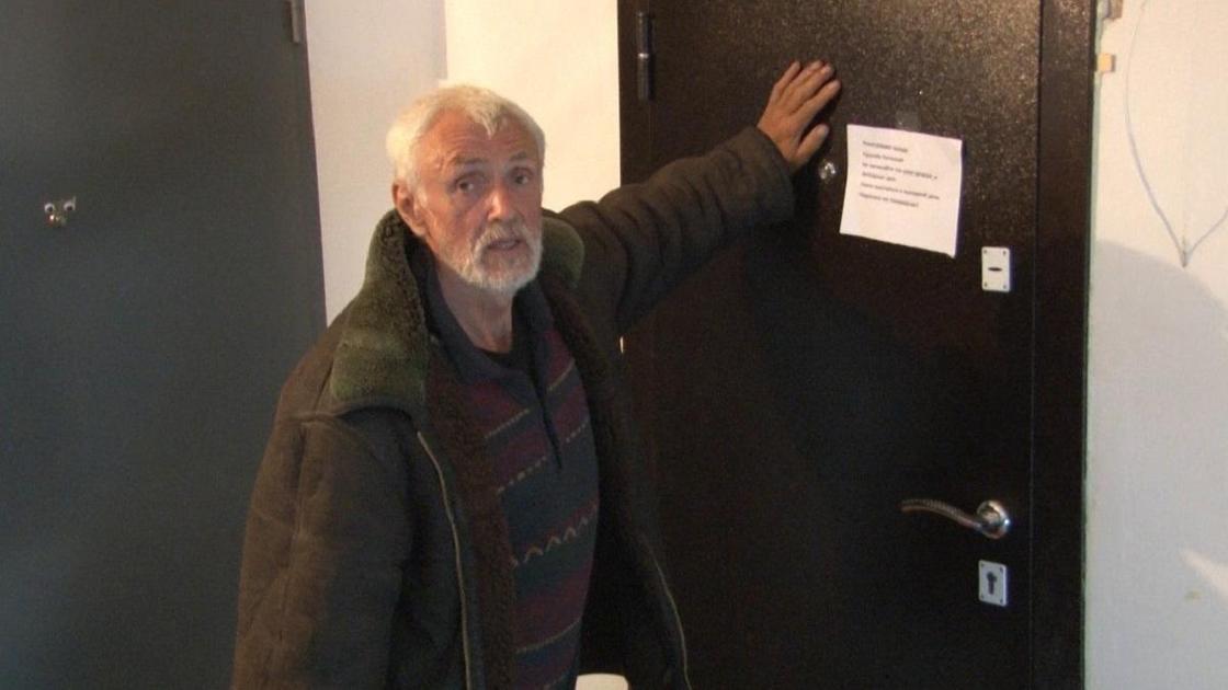 Сергей Карпухин стоит возле двери своей бывшей квартиры