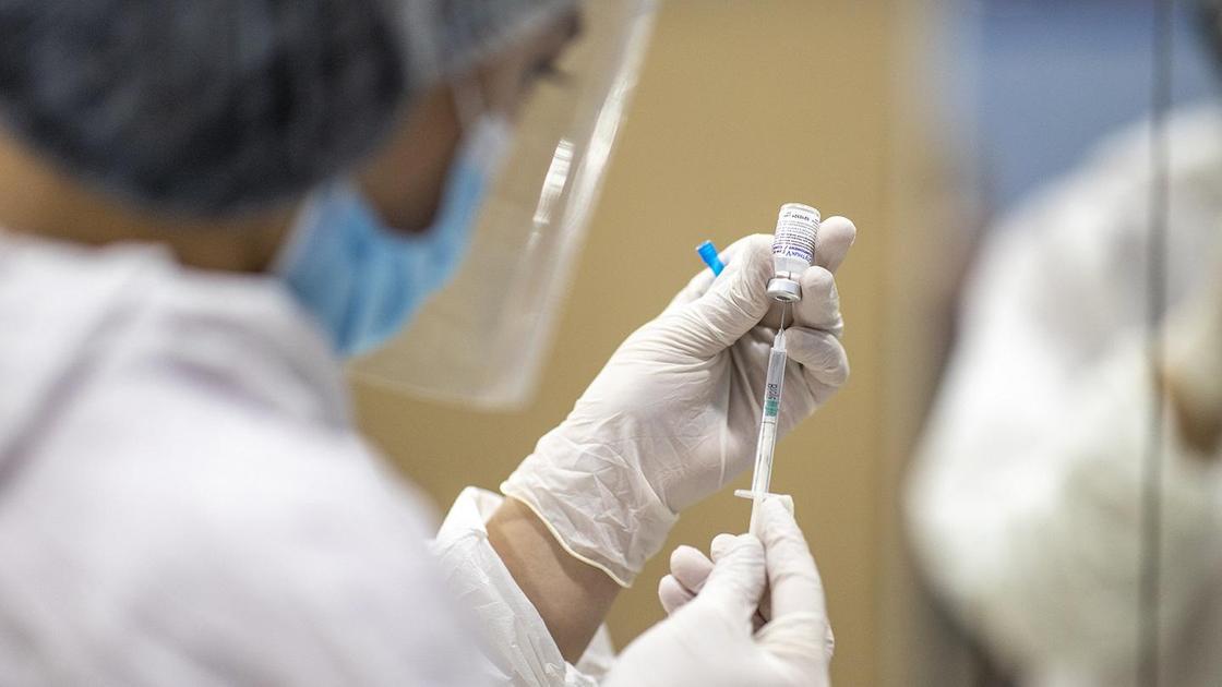 Медик набирает жидкость из ампулы в шприц