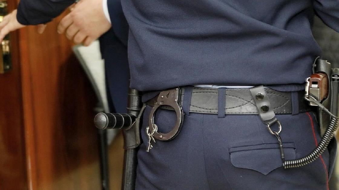 Полицейский в форме со спины с пистолетом и наручниками