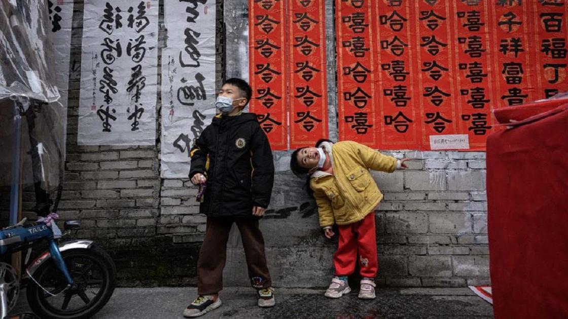 Мальчик и девочка возле стены с иероглифами
