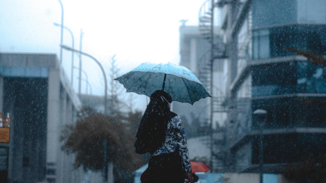 Женщина идет под дождем с зонтом