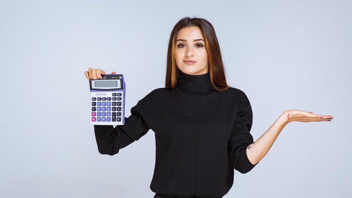 Девушка в черной блузке показывает кулькулятор