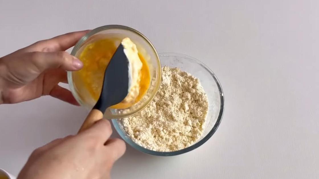 В миску с масляной крошкой добавляют сметанно-яичную смесь