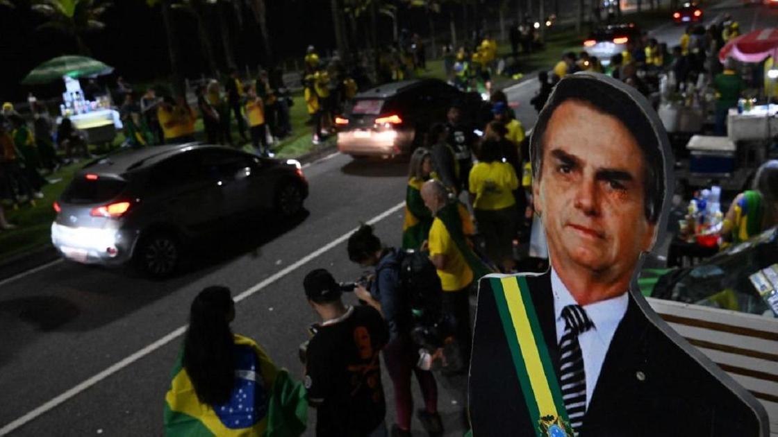 Люди на улице с бразильскими флагами и картонная фигура Жаира Болсонару