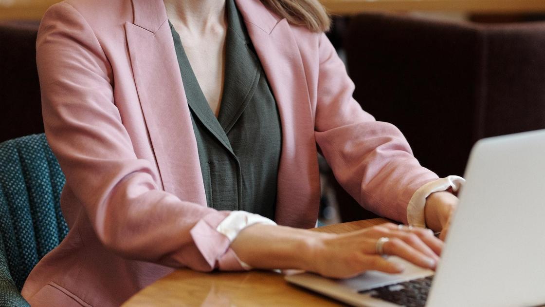 Женщина в деловом костюме сидит за ноутбуком