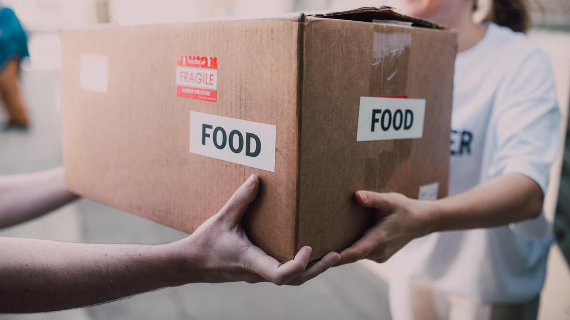 Волонтеры передают коробку с едой
