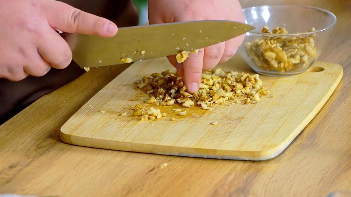 Ядра грецких орехов измельчают на разделочной доске ножом