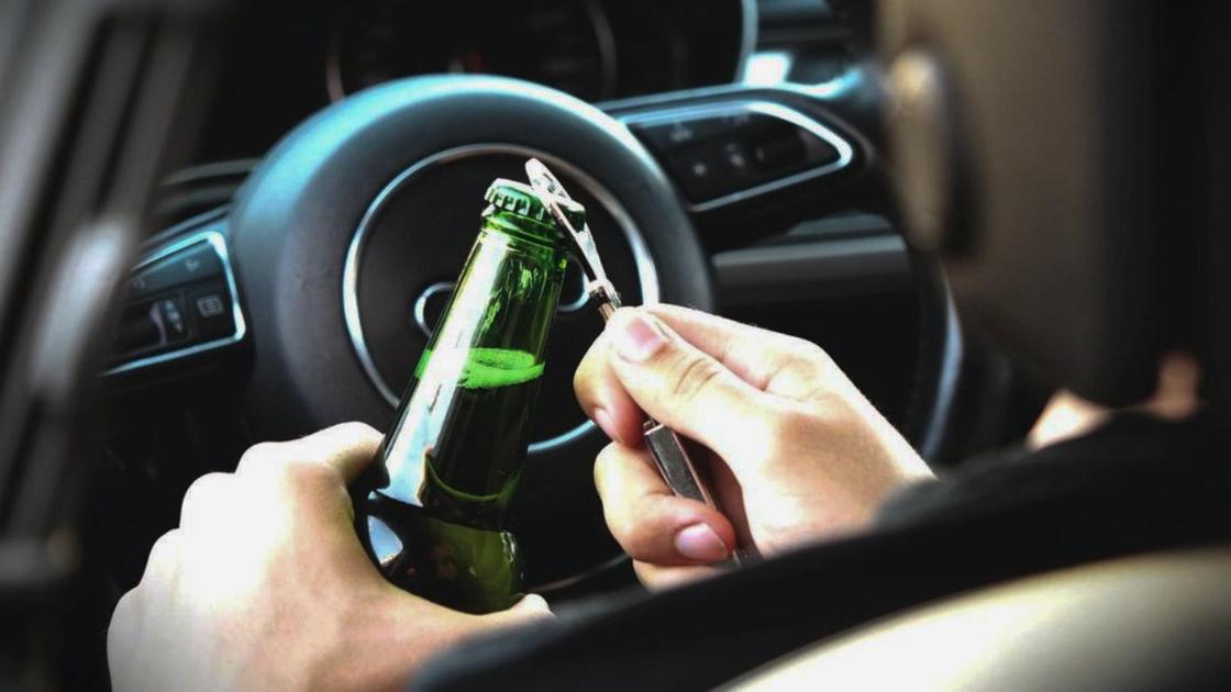 Водитель открывает бутылку пива в машине