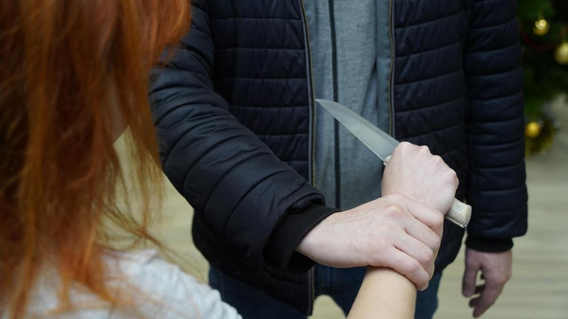 Женщина держит в руке нож рядом с мужчиной