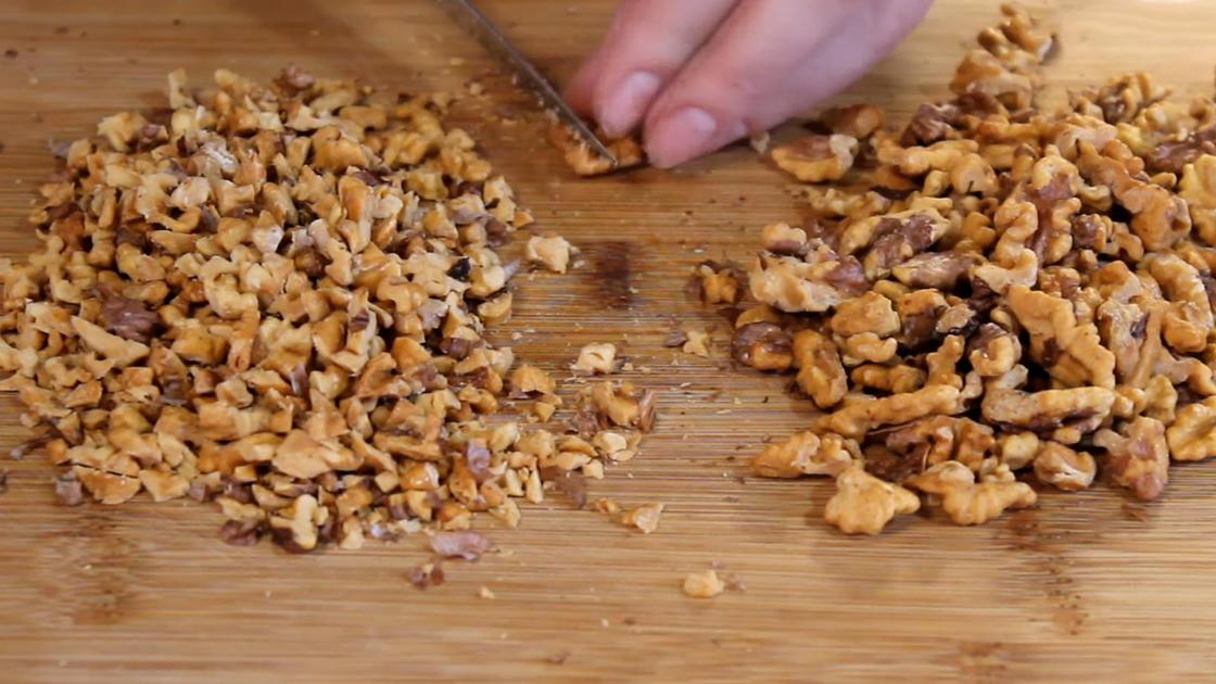 Орехи нарезают ножом на разделочной доске
