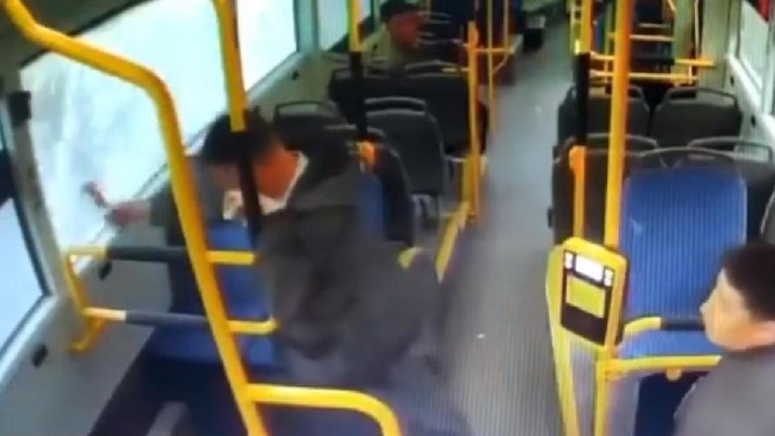 Мужчина разбивает окна в автобусе молотком