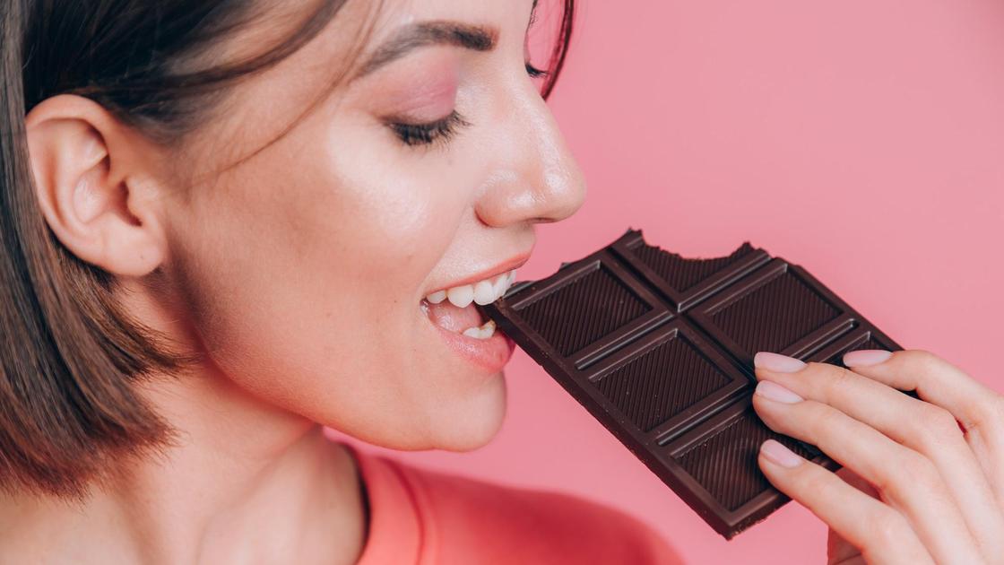 Девушка ест темный шоколад