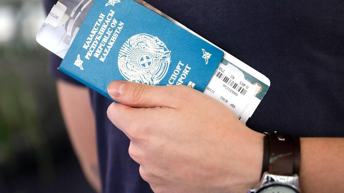 Мужчина держит в руках заграничный паспорт Республики Казахстан